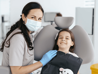 a woman in a mask and gloves is smiling at the camera