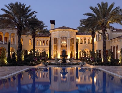 Grand elegant mansion in Florida with a swimming pool and palm trees in the evening