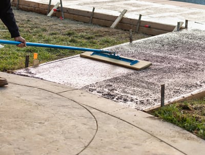 a person using a broom to clean a sidewalk