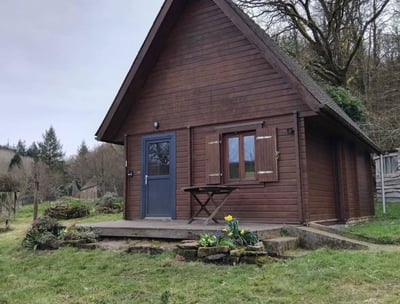 Wooden lodge nestled in nature at Les Vieilles Forges campsite in Brittany, featuring a private deck