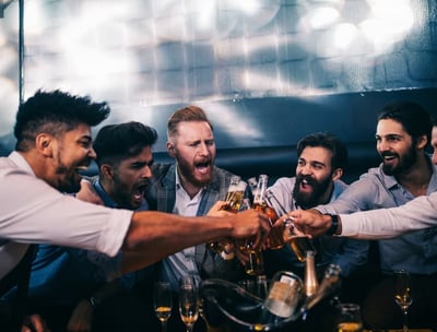 Group of men celebrating with drinks on a bachelor party bus crawl, enjoying a lively and fun night out.