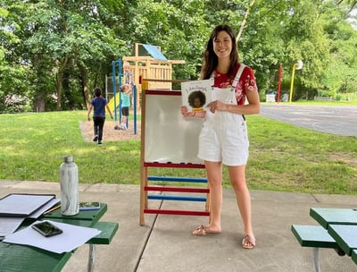 Young woman holding a children's book for a reading in the park event at Crescent Hills park