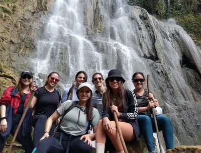 a group of people standing around a waterfall