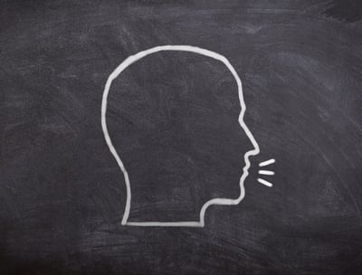 a chalkboard with the drawing of a head in profile talking