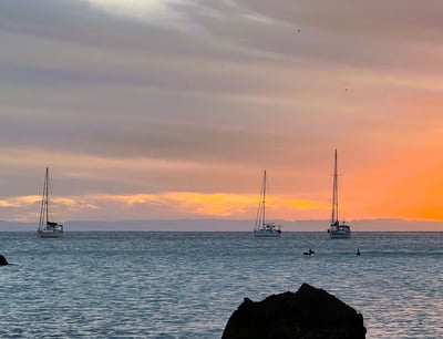 a sunset with sailboats in the water