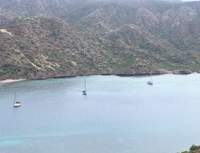 a group of boats in the water near a mountain