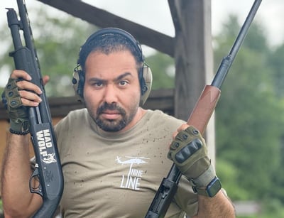 a man in a tan shirt holding two guns