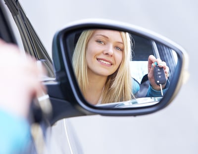 a woman is holding a keychain and looking in the mirror after passing her driving test 1st time