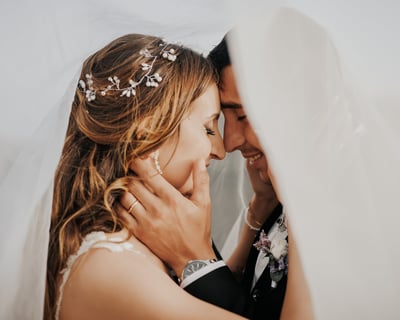 sposo e sposa abbracciati sotto al velo