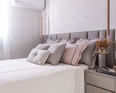Quarto sofisticado com tons neutros e rosados, iluminação pendente elegante e detalhes que garantem aconchego e requinte.