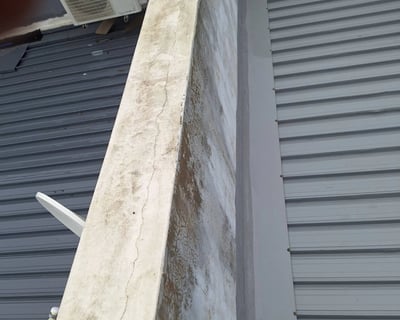 Cracks at parapet wall where waterproofing has failed on a flat roof slab