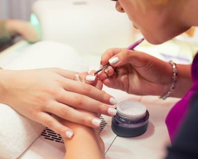 A lady receiving a nail treatment from a meticulous manicurist