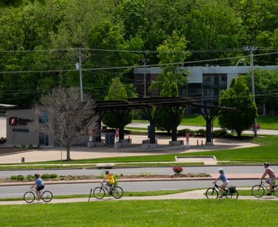 People biking on a sidewalk near a road