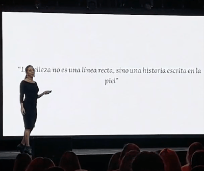 a woman standing on a stage with a white screen Dra Flavia Ward