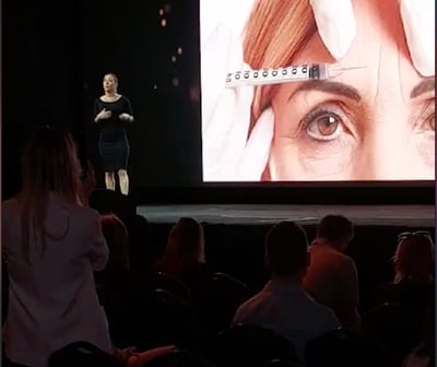 a woman is standing in front of a large screen Dra Flavia Ward