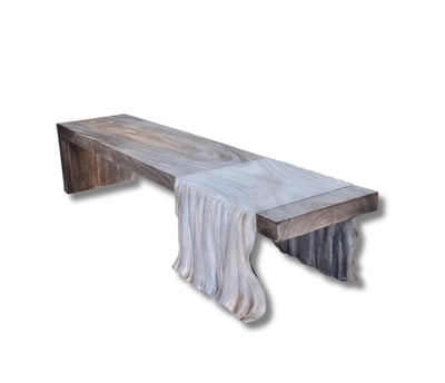 a wooden bench with a blanket draped over it