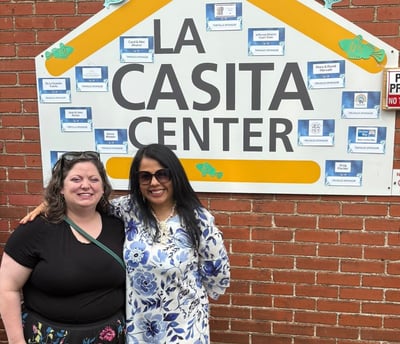 Two women standing in front of the La Casita Center building signage