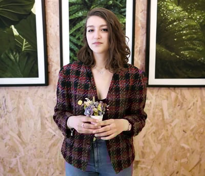 a woman standing in front of a wall with three framed pictures veste vintage en tweed