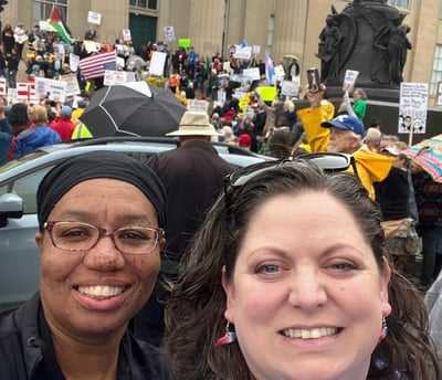 Two women standing in front of large protest group