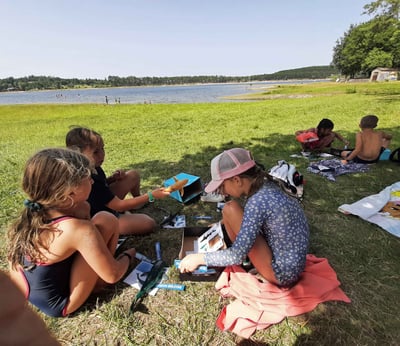 3 enfants assis près d'un lac avec la boites à requins