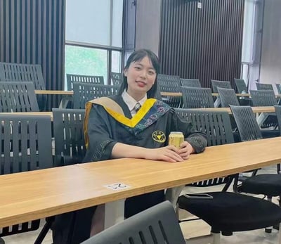 a woman in a graduation gown standing in front of a row of chairs