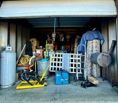 a garage with a garage door open and a lot of junk, garage, storage unit,