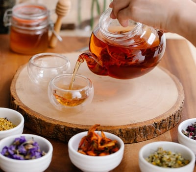 Woman brewing herb tea and white flowers on the table