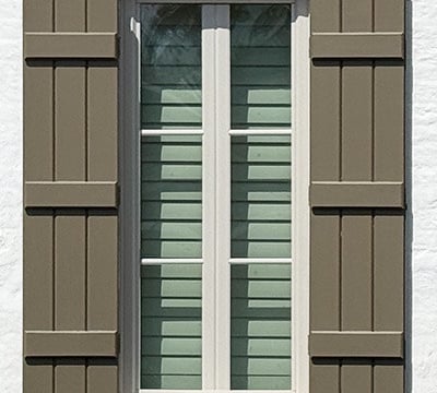 exterior board and batten shutters in brown on white brick
