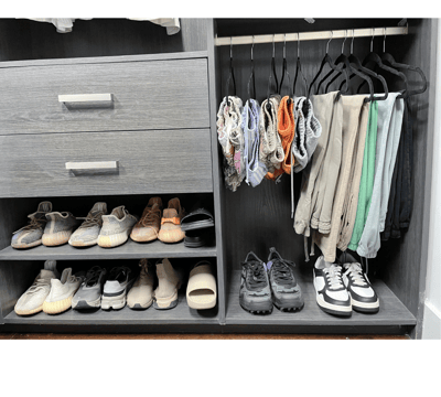 Organized closet with folded shorts, hanging pants, and neatly arranged sneakers and shoes.