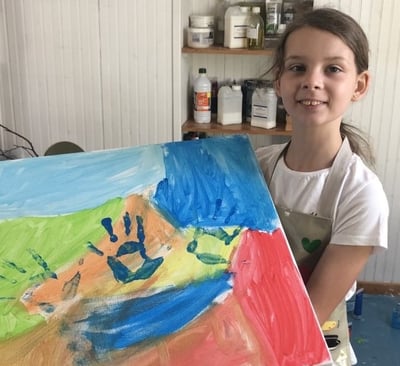 Photo de Magali STrassel, art-thérapeute, montrant une petite fille fière de montrer sa peinture
