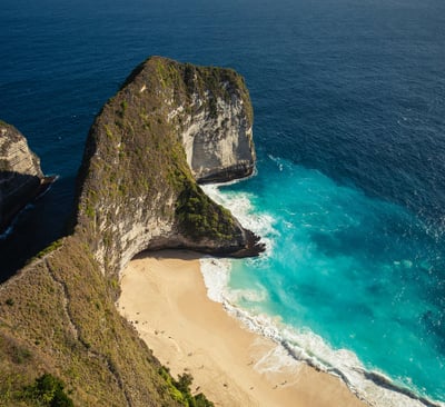 a beach with a cliff and a body of water