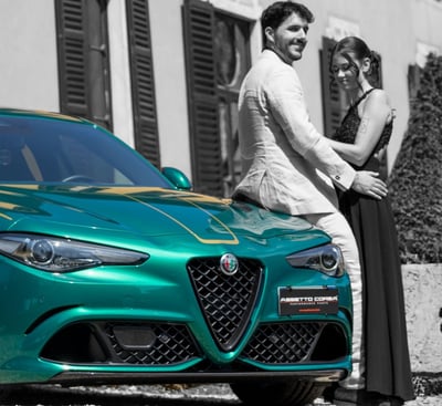 "Coppia elegante accanto a un'Alfa Romeo verde in strada di città, fotografia emozionale gaudife