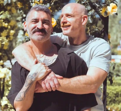 Pareja gay de hombres abrazándose y sonriendo durante una sesión de fotos de boda al aire libre en España