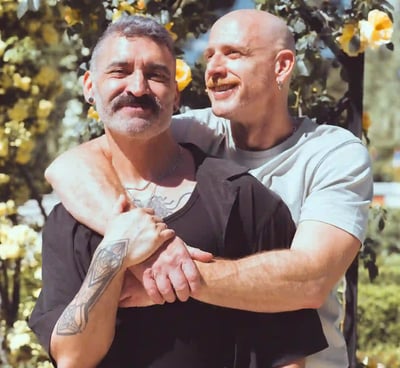 Pareja gay de hombres abrazándose y sonriendo durante una sesión de fotos de boda al aire libre en España
