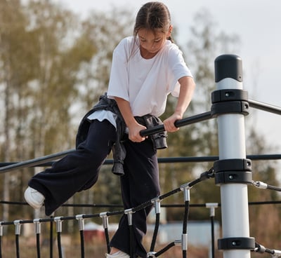 Fille grimpant sur une structure Kenguru Pro Kids Active Play en extérieur.