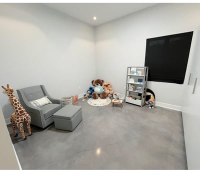 Minimalist kids’ playroom with reading corner, stuffed animals, and gray armchair.