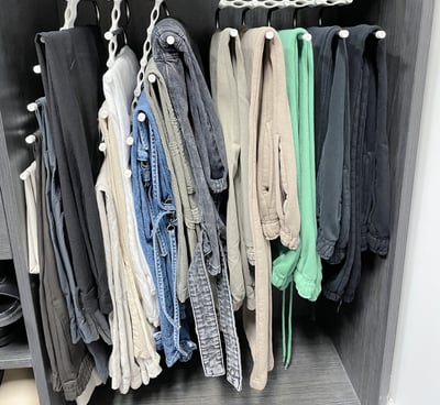 Closet section with pants neatly hung on space-saving cascading hangers.