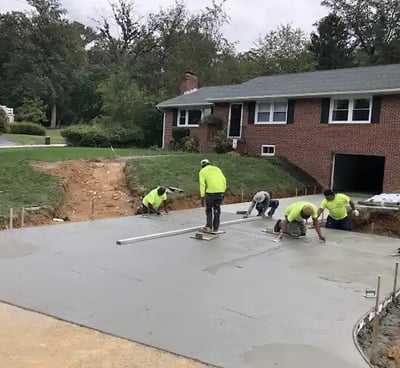 a group of men in yellow jackets and yellow jackets working on a concrete slab