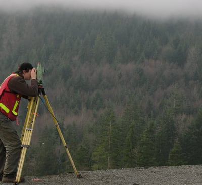 a man in a red vest and a yellow vest is holding a tripod