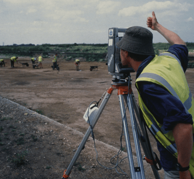 a man in a yellow vest and a camera on a tripod