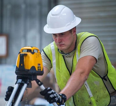 a man in a hard hat and safety vest holding a laser level