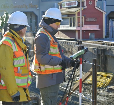 a man in a red vest and a yellow vest is holding a tripod