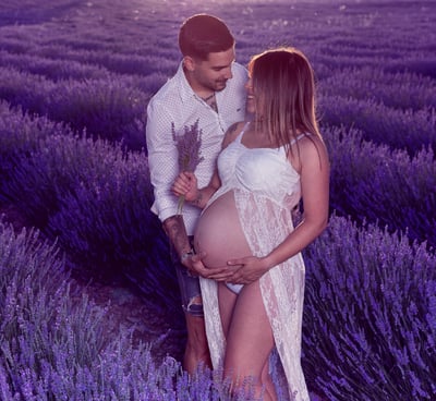 futuros papas mirandose con ternura  en  exterior y campos de lavanda, con ramo de flores en mano  