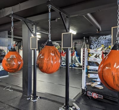 a group of punching bags hanging in a boxing gym