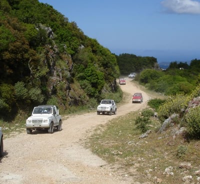 a group of cars driving down a dirt road