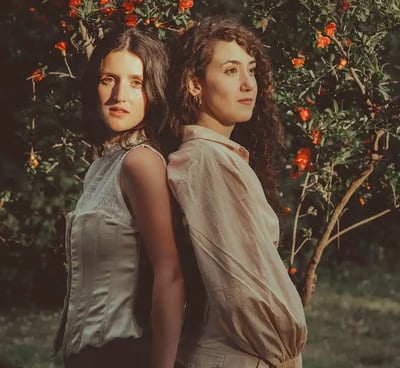Dos mujeres lesbianas en un jardín primaveral al atardecer, simbolizando el amor LGBTQ+. Bodas gay en Madrid.