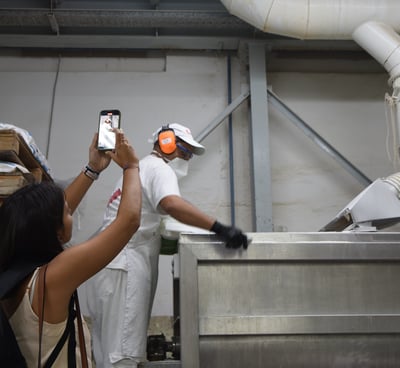 una joven filmando a un operario en una fábrica