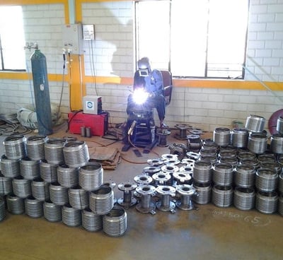 a man welding a metal pipe in a warehouse