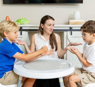 A photo of the therapist watching two boys playing scissors, paper, rock 