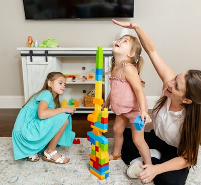 Therapist building a block tower with two sisters